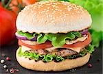 Burger with lettuce, onions, tomato and cheese on a sesame seed bun