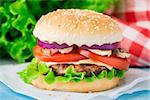 Burger with lettuce, onions, tomato and cheese on a sesame seed bun