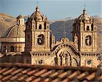 Twin towers and dome of the historic Iglesia de la Compania seen across the red rooftops of Cusco in Peru. The church dates back to 1571 and sits on top of an old Inca Palace.