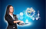 Beautiful businesswomen in suit using digital tablet. Earth with buildings and hexagons with icons. Element of this image furnished by NASA