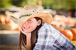Pretty Preteen Girl Wearing Cowboy Hat Portrait at the Pumpkin Patch in a Rustic Setting.