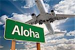 Aloha Green Road Sign and Airplane Above with Dramatic Blue Sky and Clouds.