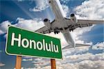 Honolulu Green Road Sign and Airplane Above with Dramatic Blue Sky and Clouds.