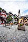 Hallstatt, Austria - August 7, 2013: Colorful houses village square with church bell tower in background, Hallstatt, Austria