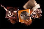 Two old vintage coffee grinder, sack with roasted coffee beans and ground coffee isolated on black background. Culinary aromatic coffee drinking.