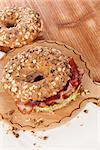 Delicious bagel eating. Whole grain bagel with bacon on wooden background.