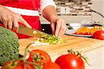 caucasian woman is cutting raw vegetables  on the kitchen table