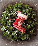 Christmas decoration with Christmas wreath and hanging stocking on snow wooden board.