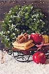 Christmas decoration with decorative sled and sweet cookies with red winter apples. Toned photo.