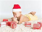 Asian baby boy with santa hat playing with Christmas present on floor.