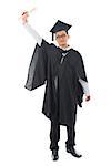 Full length Southeast Asian university student in graduation gown, standing isolated on white background.