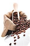 Fresh aromatic coffee beans in brown sack with wooden spoon isolated on white background. Culinary coffee drinking.