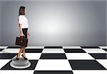 Beautiful businesswoman walking and holding briefcase. Floor with checkerboard texture and gray wall