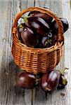 Fresh Ripe Small Eggplants In Wicker Basket on Rustic Wooden background