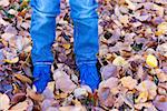 close-up of boy's feet in blue suede boots in bright yellow autumn leaves