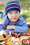 cute little boy lying in colorful autumn leaves