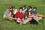 Happy male teenager studying with friends outdoors
