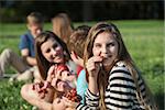 Cute young female eating grapes with group outdoors