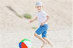 little boy playing with the ball at the beach