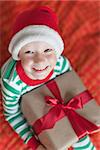 excited little boy in santa hat at christmas time at home holding nicely wrapped present