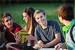 Smiling confident male teenager with friends outdoors