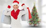 Festive woman holding shopping bags against blurry christmas tree in room