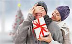 Mature woman surprising partner with gift against blurry christmas tree in room