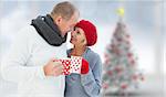 Mature couple holding mugs against blurry christmas tree in room