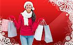 Festive brunette holding shopping bags against christmas themed snow flake frame