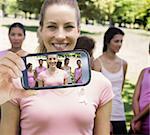 Composite image of hand holding smartphone showing photograph of breast cancer activists