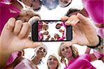 Composite image of hand holding smartphone showing photograph of breast cancer activists