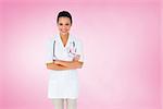 Pretty nurse with arms crossed against pink vignette