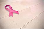 Breast cancer awareness ribbon against bleached wooden planks background