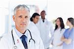 Mature doctor looking straight ahead wearing breast cancer awareness ribbon