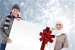 Winter couple showing poster with red christmas ribbon