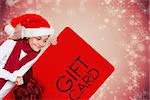 Festive little girl showing card against white snowflake design on red