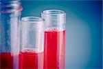 test tubes with red liquid in laboratory on blue light tint background with space for text