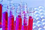 detail of pipette and test tubes with red liquid in laboratory on blue light tint background