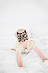 Girl wearing cat mask lying on bed