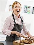 Smiling woman cutting bread in kitchen