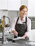 Smiling woman washing dishes