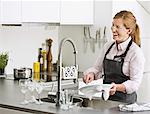 Smiling woman washing dishes