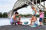 Woman with girls grilling at river