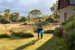 Woman walking with bucket near house