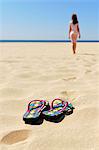 Flip flops on beach, girl on background