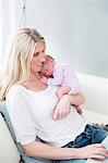 Woman holding newborn daughter and using laptop