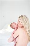 Woman kissing newborn daughter