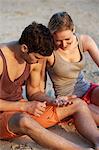 Young couple on beach looking at shells