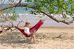 Young woman using laptop in hammock on beach