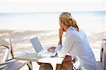 Young woman on beach using laptop